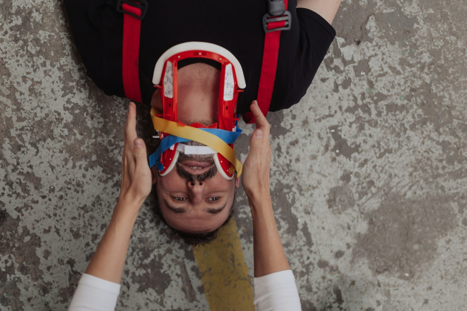 an injured man lies on a concrete floor with a neck brace
